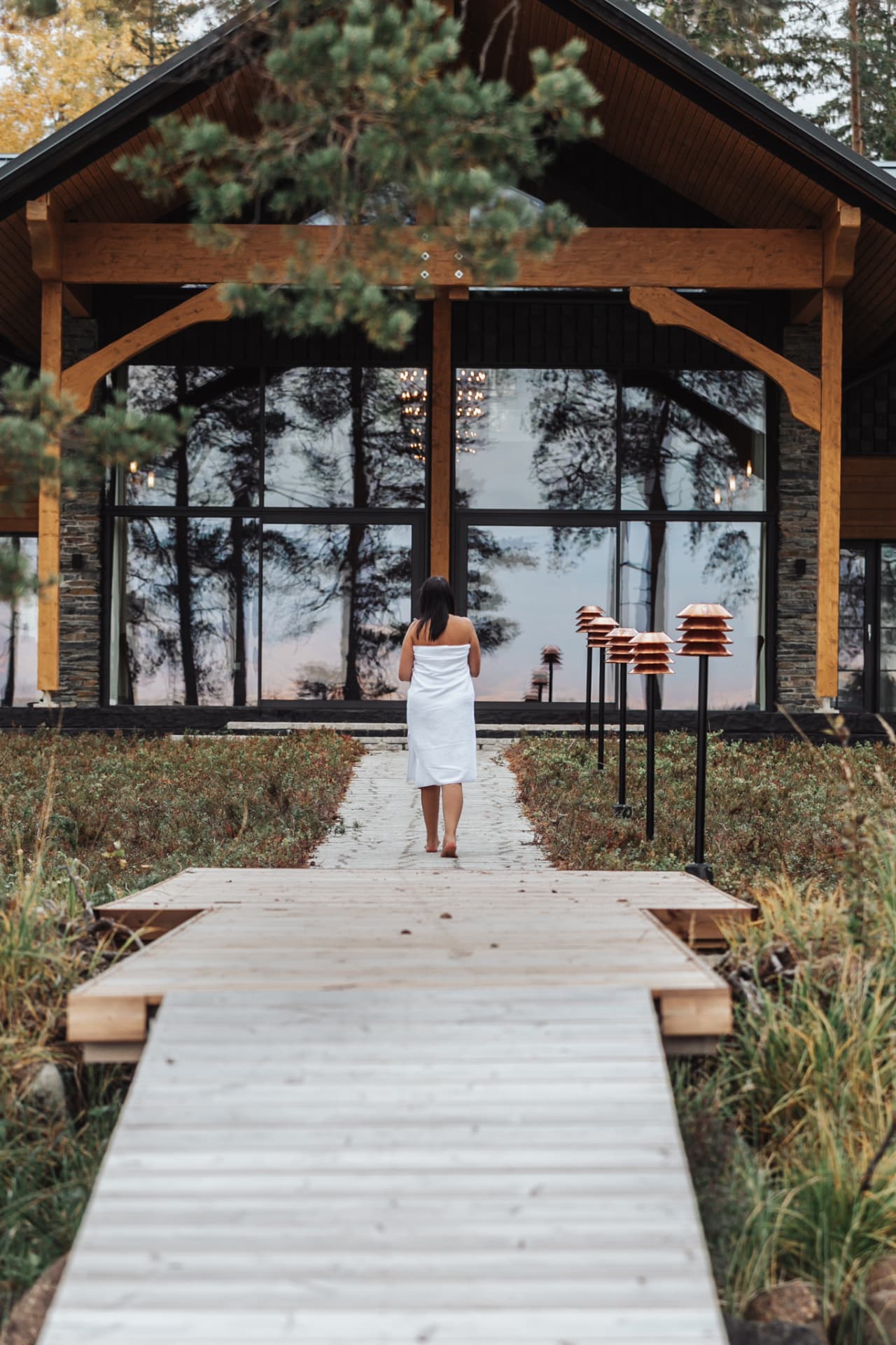Guest walking the boardwalk to the lakeside spa house, the Finnish sauna ritual at Neituri Manor