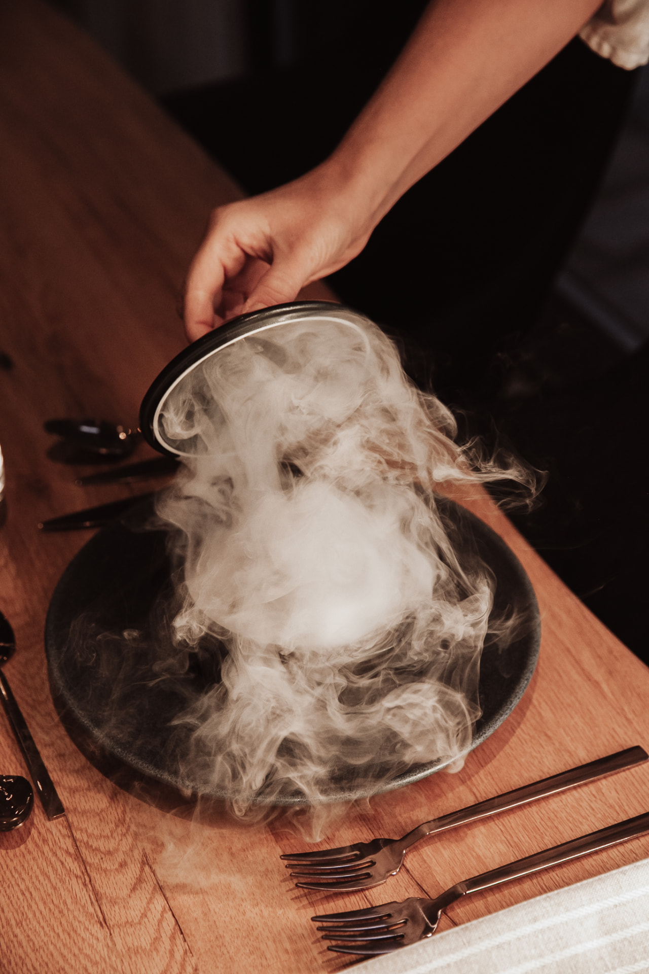 Smoke lifting from a plate as the cloche is raised, private chef dining at Neituri Manor in Finland