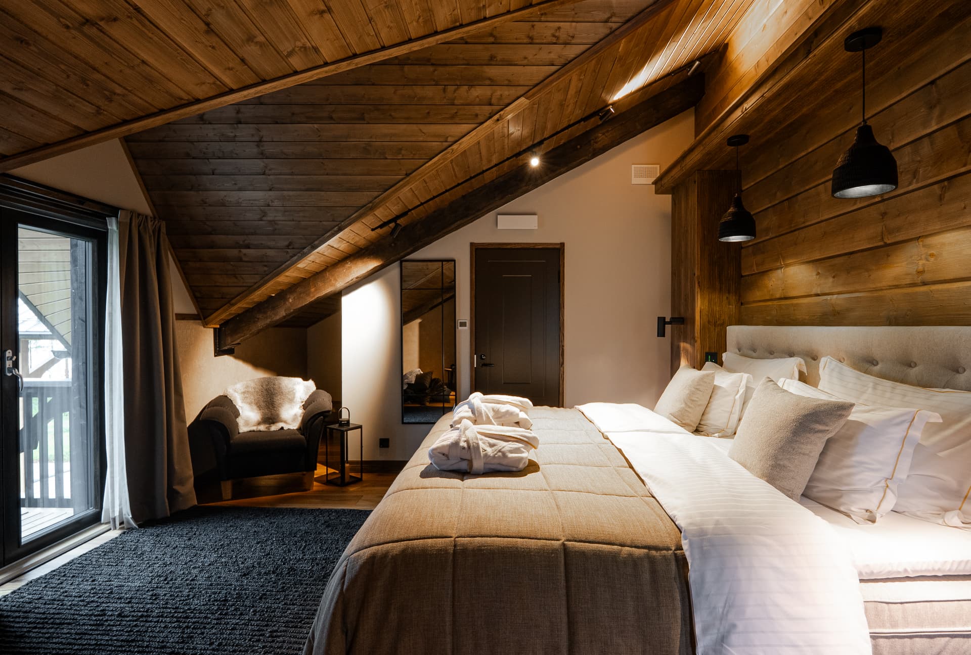 Attic suite with timber beams and a balcony door at Neituri Manor, Finnish design in the countryside